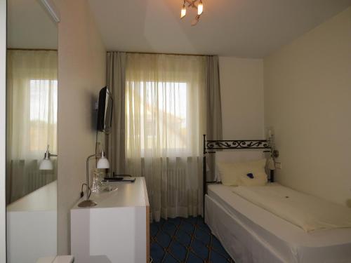 Schlafzimmer mit einem Bett, einem Waschbecken und einem Spiegel in der Unterkunft Hotel & Restaurant Mainaublick in Uhldingen-Mühlhofen