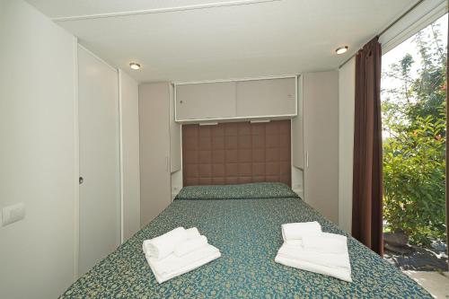 a bedroom with a bed with two white towels at Agricampeggio Corte Tonolli in Valeggio sul Mincio