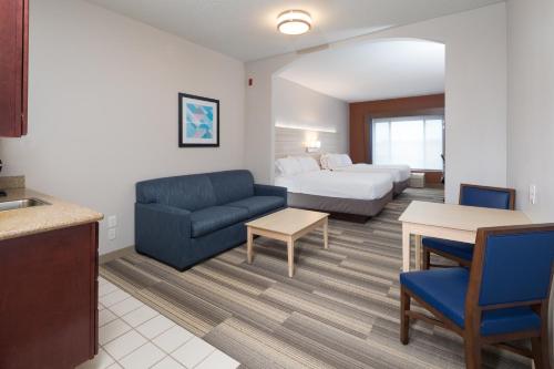 a hotel room with a bed and a blue couch at Holiday Inn Express Hotel & Suites Detroit-Utica by IHG in Utica