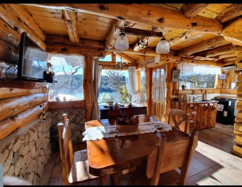 a dining room and kitchen in a log cabin at costa bonita el bosque in Villa Pehuenia