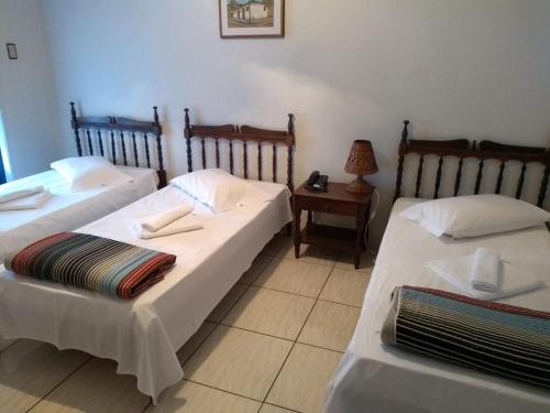 a room with two beds and a table with a lamp at Hotel Pousada São Miguel in Baependi