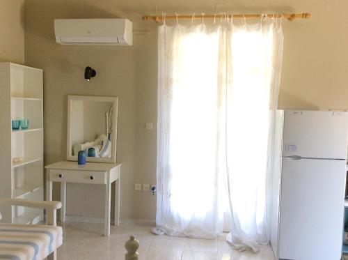 um quarto com um frigorífico branco e uma janela em Kefalonia apartments: cute studios in orchard, Spartia em Spartià