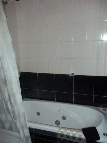 a bathroom with a white tub and a black and white tiles at La Posada del Mar in Miramar