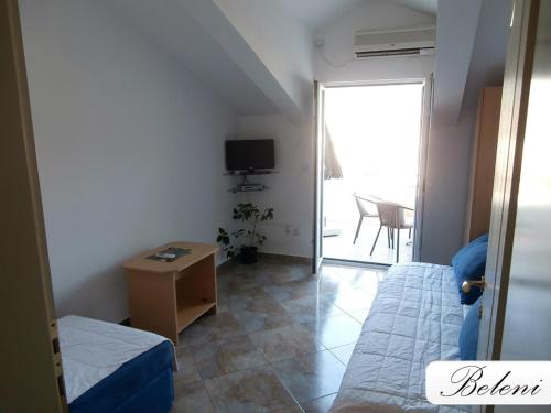 Habitación pequeña con cama, mesa y TV. en Apartments Beleni, en Herceg-Novi