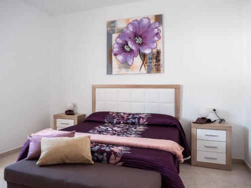 une chambre avec un lit et un tableau de fleurs sur le mur dans l'établissement Casa Bárbara, à Tías