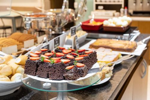 a buffet with a chocolate cake with strawberries on it at Hotel Negrini in Balneário Camboriú