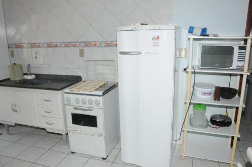 cocina con nevera blanca y microondas en Residencial Gil, en Palhoça