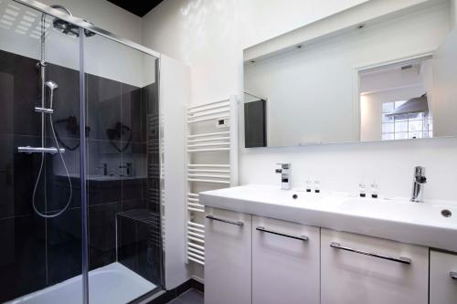 a white bathroom with a shower and a sink at Appartement rue de Rennes - Gaîté in Paris