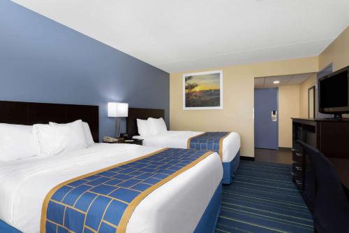 a hotel room with two beds and a flat screen tv at Days Inn by Wyndham Augusta in Augusta