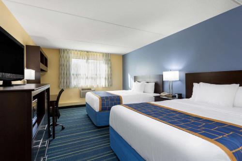 a hotel room with two beds and a flat screen tv at Days Inn by Wyndham Augusta in Augusta