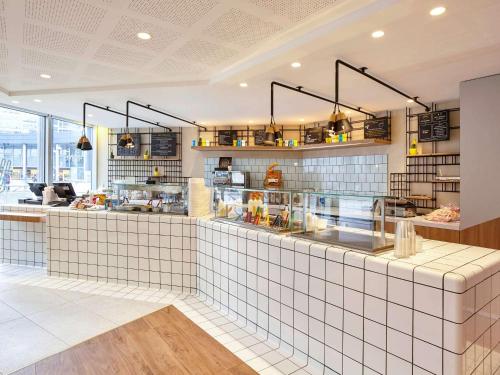 a restaurant with a white tiled counter in a room at Mercure Paris la Défense Grande Arche in Nanterre