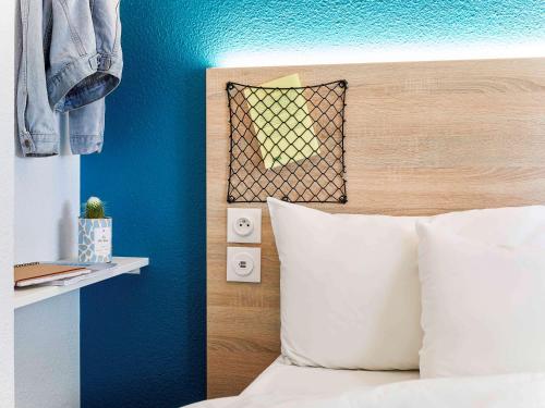 a bedroom with a bed with a blue wall at hotelF1 Mulhouse Bâle Aéroport in Saint-Louis