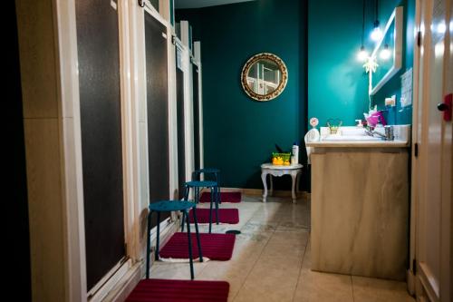 La salle de bains est pourvue de tabourets rouges et bleus et d'un lavabo. dans l'établissement La Flamenka Hostel, à Séville