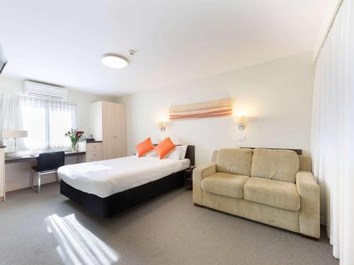 a bedroom with a bed and a couch and a chair at Tall Trees Ainslie Motel in Canberra