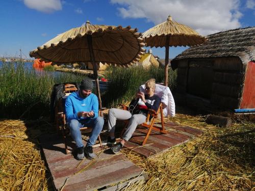 two people sitting in chairs under an umbrella at Urosfood & Titiqaqa Lodge in Uros