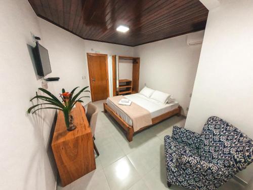 a bedroom with a bed and a chair in it at Amarilis Pousada Arraial d'Ajuda in Arraial d'Ajuda