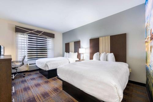 a hotel room with two beds and a desk at Clarion Pointe Madison-Huntsville in Madison