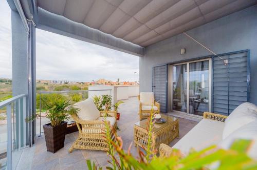 a balcony with wicker chairs and tables on a patio at Holiday Home in Residence KOMA in Torrevieja
