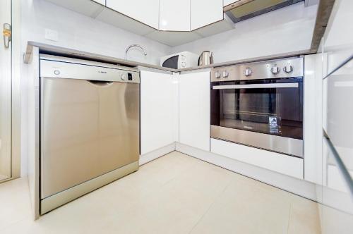 a kitchen with stainless steel appliances and white cabinets at Holiday Home in Residence KOMA in Torrevieja
