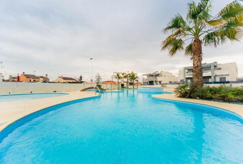 a large swimming pool with blue water and palm trees at Holiday Home in Residence KOMA in Torrevieja