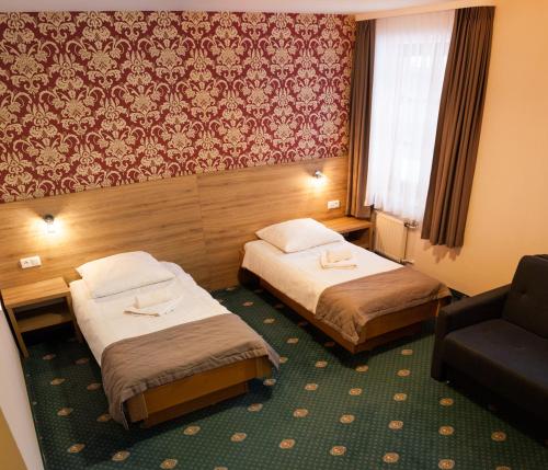 a hotel room with two beds and a chair at Hotel Fero Lux in Korbielów