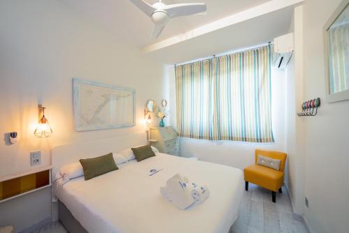 a bedroom with a white bed and a yellow chair at BetiJai - Basque Stay in San Sebastián
