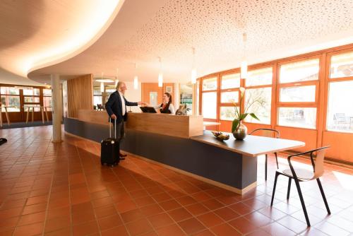 a man with a suitcase standing at a counter in a lobby at Hohenwart Forum in Pforzheim