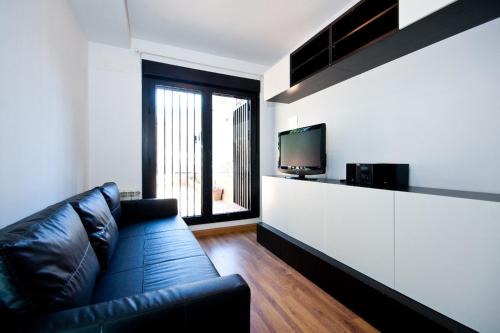 a living room with a black leather couch and a television at Charming Madrid Urgel in Madrid