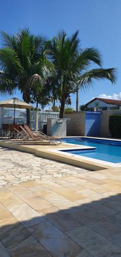 a swimming pool with lounge chairs and palm trees at Cananeia Residencial in Cananéia