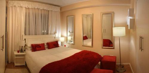 a bedroom with a large bed with red pillows at La Loggia Gateway Apartments in Durban