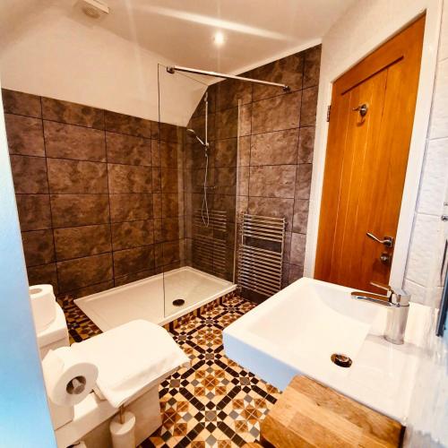 a bathroom with a sink and a toilet and a shower at The Old Lodge in Stroud