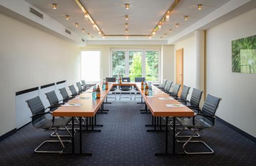 a large conference room with long tables and chairs at Parkhotel am Taunus in Oberursel