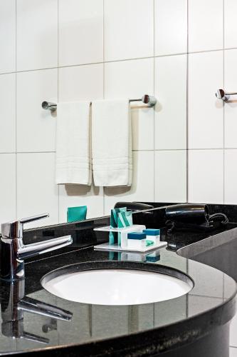 a bathroom counter with a sink and a mirror at Firenze Business Hotel in Palhoça