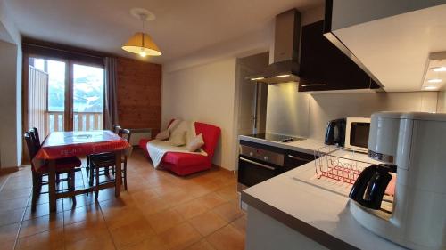cocina y sala de estar con mesa y sofá en Appartement neuf avec terrasse sur Praloup 1600 en Uvernet