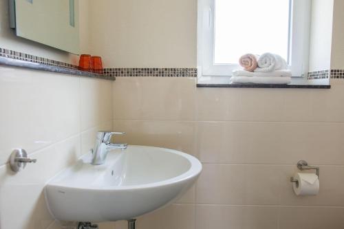 ein weißes Bad mit einem Waschbecken und einem Fenster in der Unterkunft Haus Strandburg Seebriese in Dahme