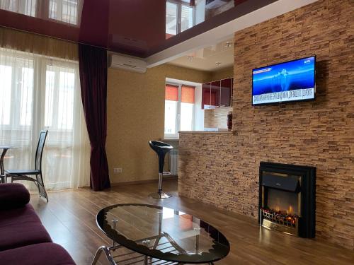 a living room with a fireplace and a tv on a brick wall at New apartments with panoramic views on Avenue Nauky in Kharkiv