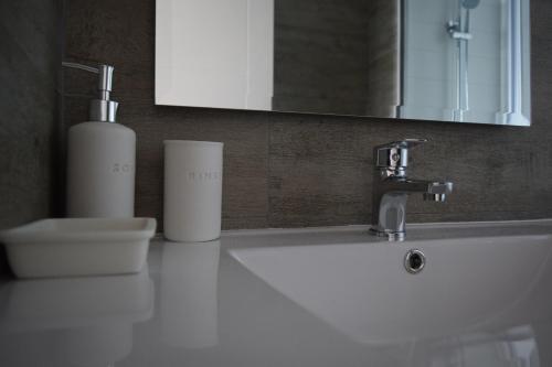 een wastafel in de badkamer met een zeepdispenser en een spiegel bij Pura Vida - nuevo apartamento con salida directa a la costa in Concón