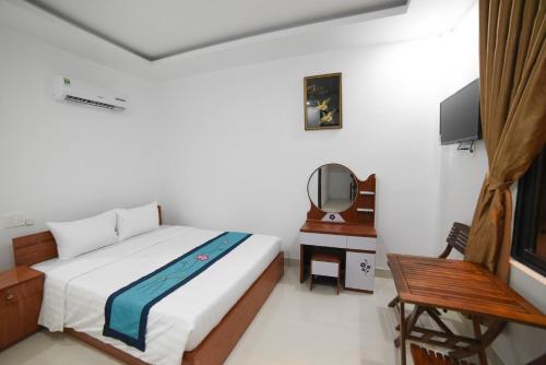 a bedroom with a bed and a mirror and a tv at Asean Garden Homestay Hue in Hue