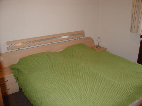 Bett mit grüner Decke in einem Schlafzimmer in der Unterkunft Type Robinson in Ronshausen