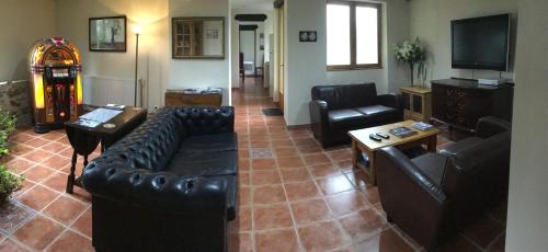 a living room with black leather furniture and a television at The Magnolias B&B in Moyon