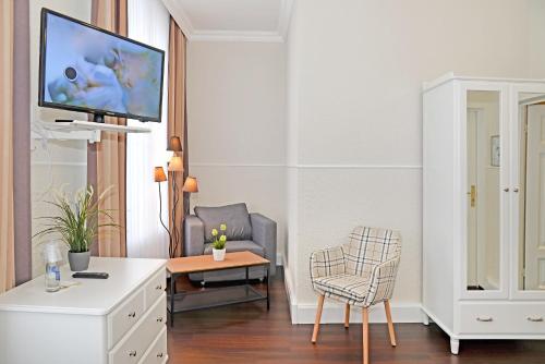 a living room with a tv and a chair at Hotel Stralsund in Stralsund