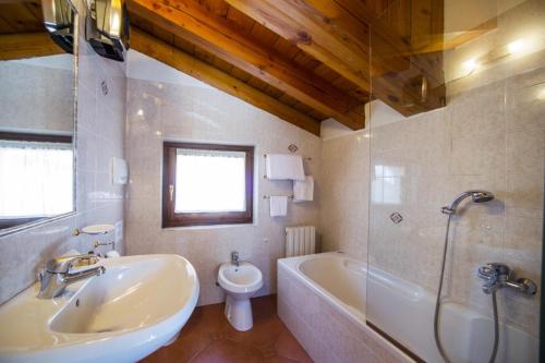 a bathroom with a sink and a tub and a toilet at Hotel Chalet Joli in Courmayeur