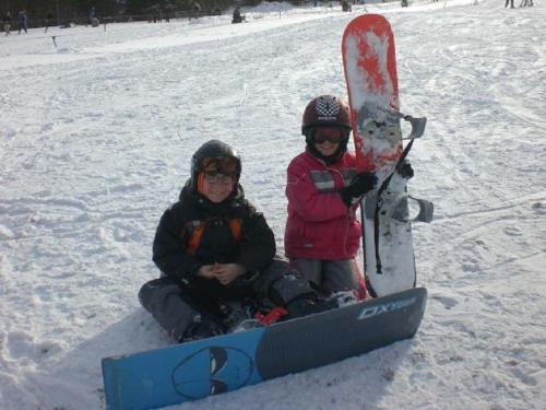 two people sitting in the snow with a snowboard at Typ Murmeltier in Schmallenberg