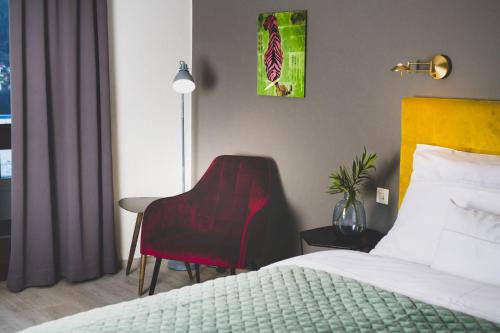 a hotel room with a bed and a red chair at Hotel Parks in Velden am Wörthersee