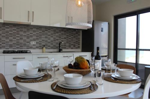 a white kitchen with a table with wine glasses at Harmony apartment in Mindelo São Vicente in Mindelo