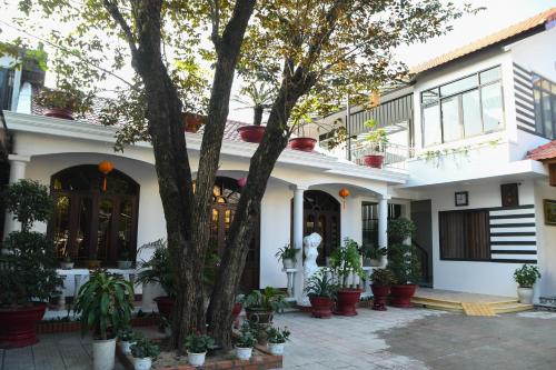 a house with potted plants and a tree at Asean Garden Homestay Hue in Hue