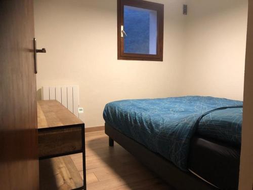 1 dormitorio con cama, mesa y ventana en Blaise 3 pièces, en Saint-Étienne-de-Tinée