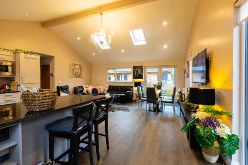 a kitchen and living room with a counter and chairs at Settlers Lodge in Otterburn