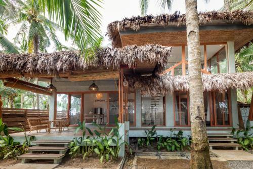 a resort with a thatched roof and palm trees at Punta Punta Surf Retreat in General Luna