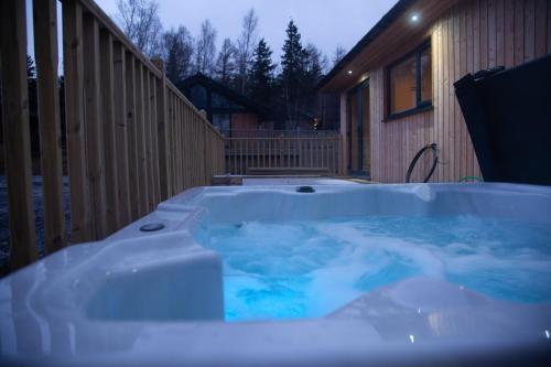 a hot tub in front of a house at Settlers Lodge in Otterburn